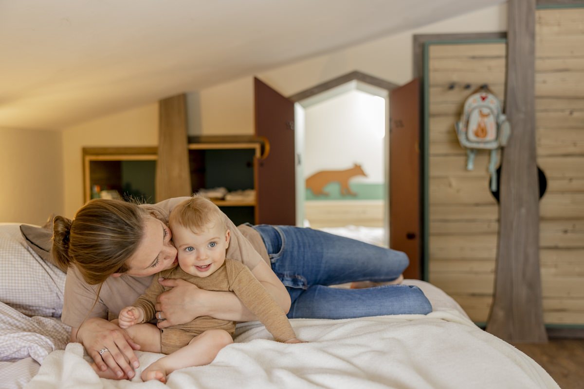 eine Mutter kuschelt auf dem Bett ihres Ferienhauses mit ihrem Baby | Foto: Hanna Witte