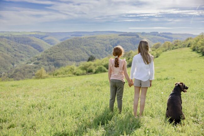 zwei Mädchen stehen Hand in Hand mit einem Hund von Hof Hardthöhe auf einer Wiese und schauen aufs Mittelrheintal | Foto: Hanna Witte