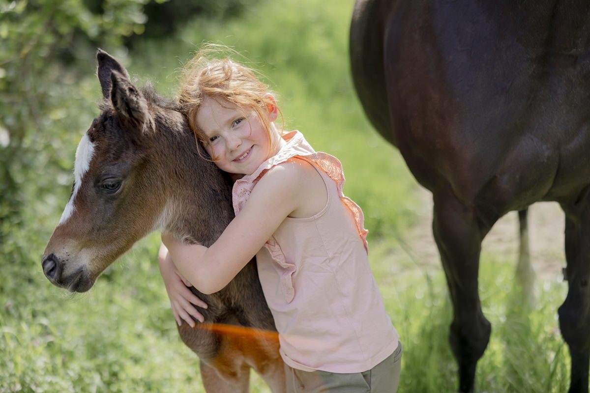ein Mädchen umarmt ein Fohlen auf dem Ferienhof Hardthöhe | Foto: Hanna Witte