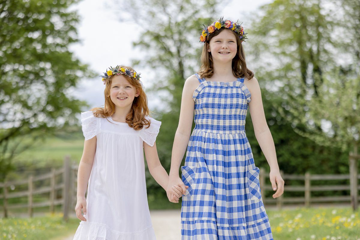 zwei Mädchen mit Blumenkränzen im Haar laufen Hand in Hand über das Gelände von Ferienhof Hardthöhe | Foto: Hanna Witte