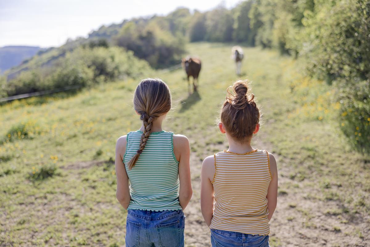 zwei Mädchen beobachten Pferde, die über die Wiese von Ferienhof Hardthöhe gehen | Foto: Hanna Witte