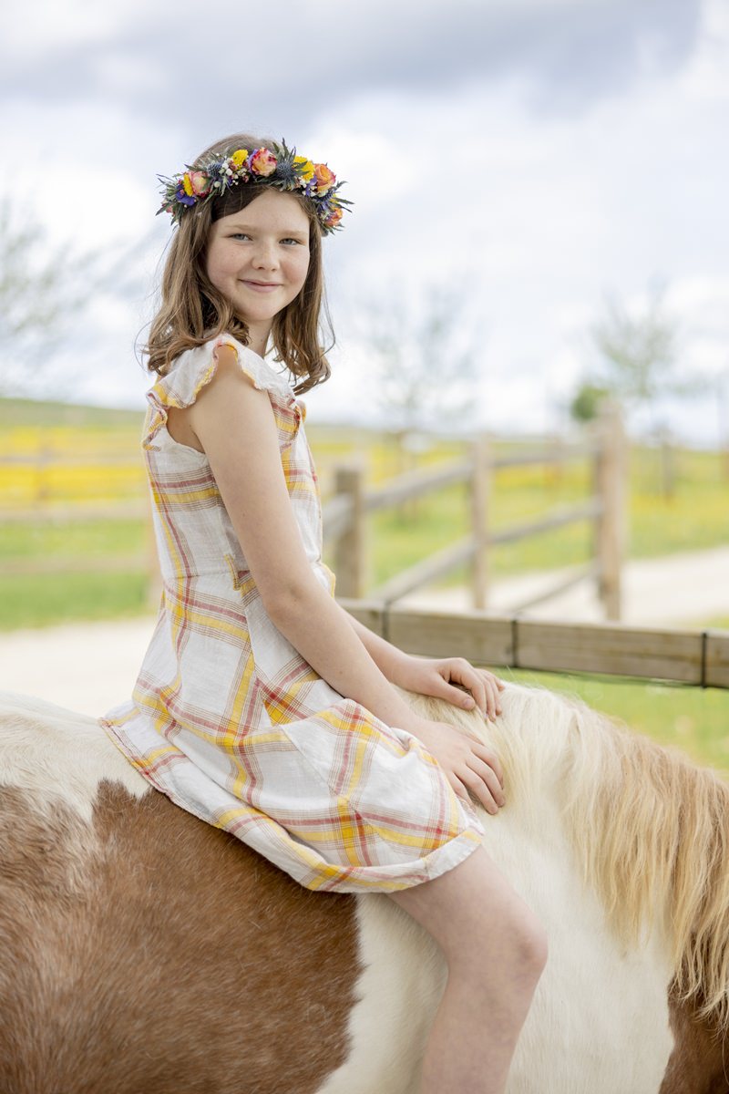 ein Mädchen mit Blumenkranz im Haar sitzt auf einem Pferd von Ferienhof Hardthöhe | Foto: Hanna Witte