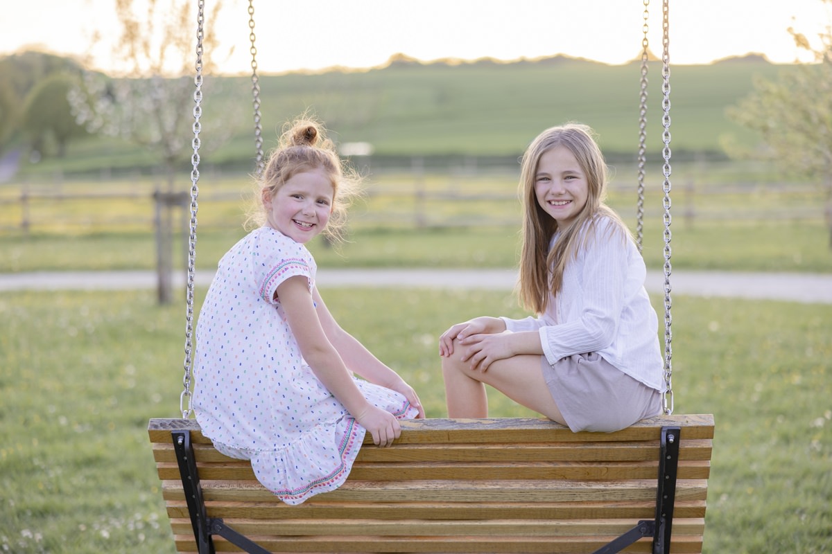 zwei Mädchen sitzen auf einer Gartenschaukel des KInderhotels Ferienhof Hardthöhe | Foto: Hanna Witte