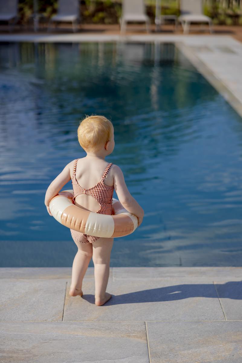 ein kleines Mädchen läuft mit einem Schwimmreifen um ihren Hüften zum Pool von Ferienhof Hardthöhe | Foto: Hanna Witte