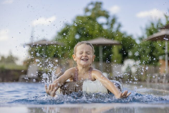 ein Mädchen plantscht ausgelassen mit einem Schwimmreifen im Pool von Familienhotel Hardthöhe | Foto: Hanna Witte