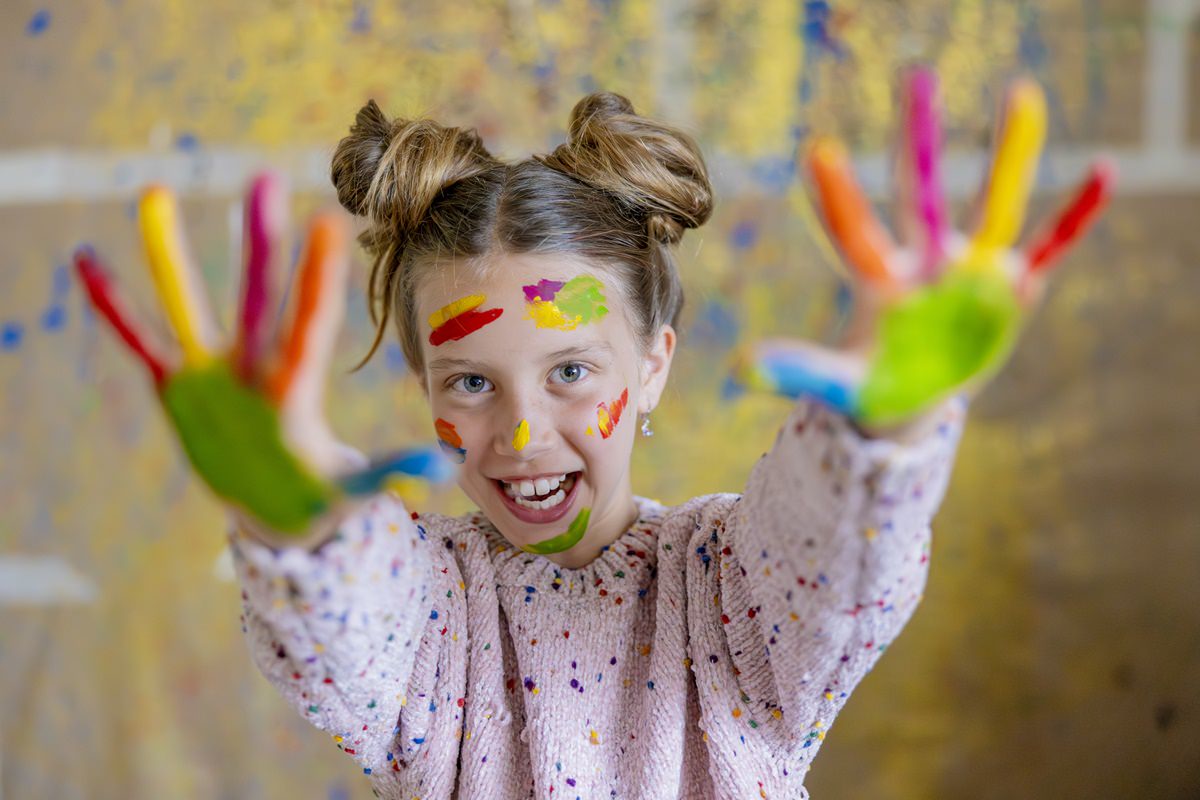 ein Mädchen in der Syltklinik hat Farbe im Gesicht und bunt bemalte Hände | Foto: Hanna Witte