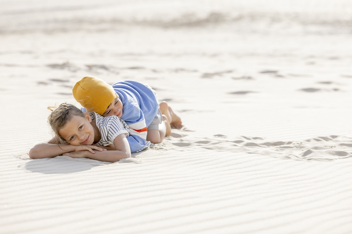 zwei Kinder schmiegen sich am Strand aneinander | Foto: Hanna Witte