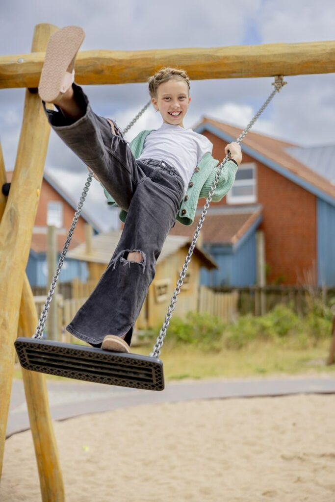 ein Mädchen schaukelt im Stehen auf dem Spielplatz der Syltklinik | Foto: Hanna Witte