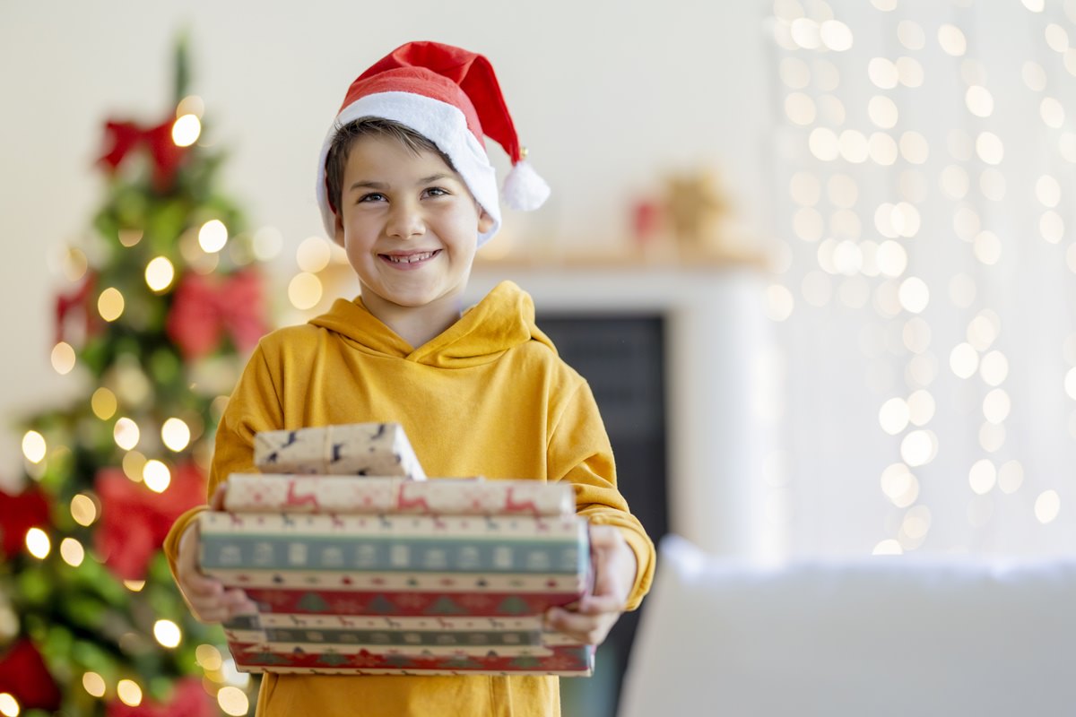 ein Junge mit Nikolausmütze hält drei Geschenke in der Hand | Foto: Hanna Witte