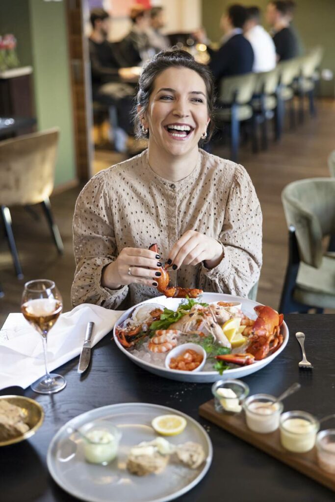 eine lachende Frau isst in einem Restaurant Meeresfrüchte von einer großen Platte | Foto: Hanna Witte