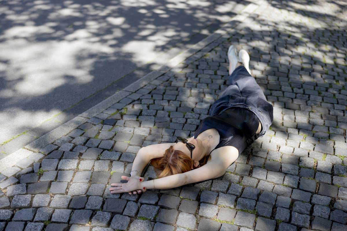 eine Yoga Lehrerin liegt entspannt auf einem Gehweg | Foto: Hanna Witte