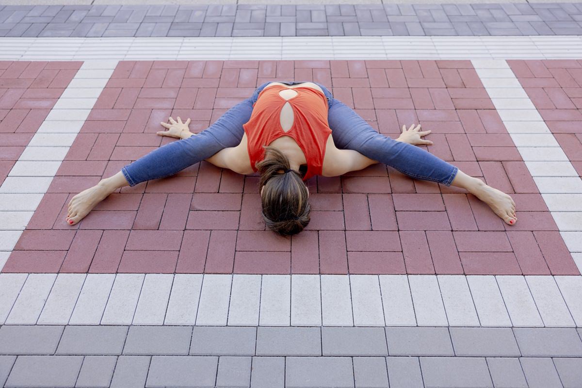 eine Frau macht das Yoga Asana Upavistha Konasana auf einem Gehweg | Foto: Hanna Witte