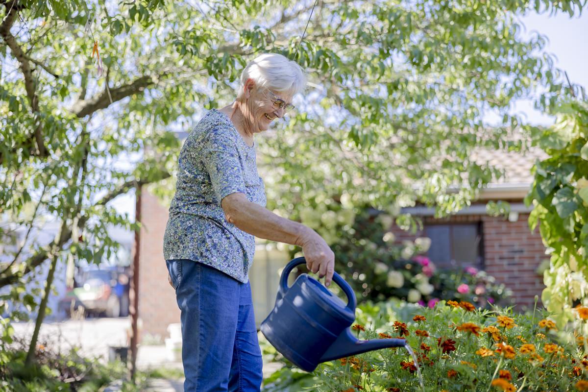 die Großmutter einer Landwirtsfamilie gießt die Blumen in einem Beet | Foto: Hanna Witte